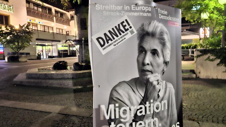 Plakat von Spitzenkandidatin Marie-Agnes Strack-Zimmermann mit "Danke"-Aufkleber am Rathausplatz in Grünwald